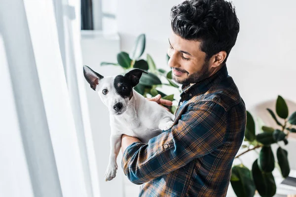 Smiling and handsome bi-racial man holding Jack Russell Terrier — Stock Photo