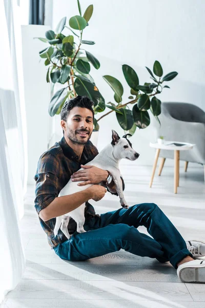 Smiling and handsome bi-racial man holding Jack Russell Terrier — Stock Photo