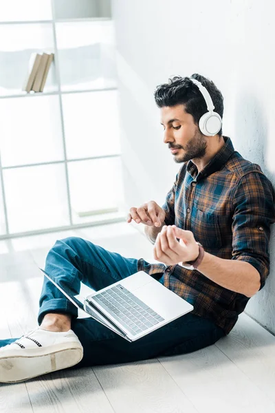 Schöner Mann mit zwei Rassen und Laptop, der Musik hört und das Spiel auf der Gitarre imitiert — Stockfoto