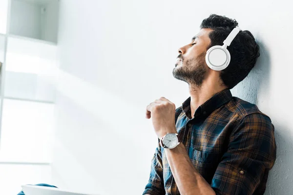 Bonito bi-racial homem com fechado olhos ouvir música no apartamento — Fotografia de Stock