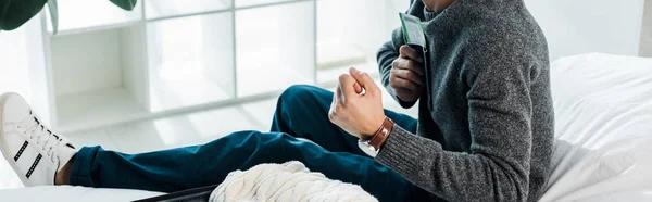 Panoramic shot of bi-racial man in sweater holding passport with air ticket and showing yes gesture — Stock Photo