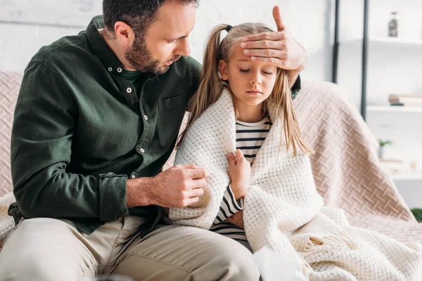 Attentive father touching forehead of diseased daughter — Stock Photo