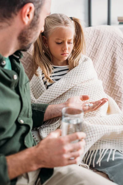 Selective focus of man giving pills to upset, diseased daughter — Stock Photo