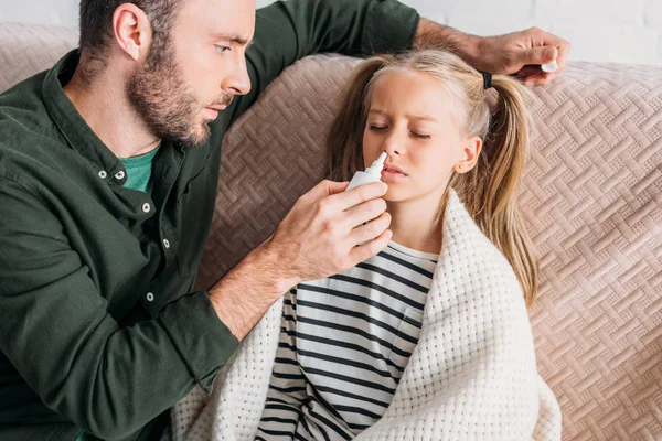 Cuidado padre sosteniendo aerosol nasal cerca de hija enferma - foto de stock