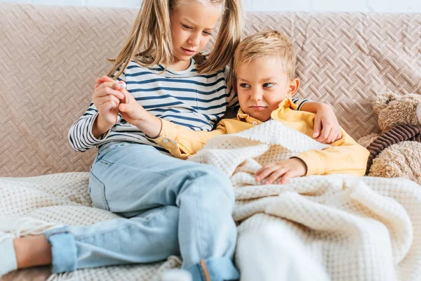 Atenta hermana celebración píldora cerca enfermo, disgustado hermano - foto de stock