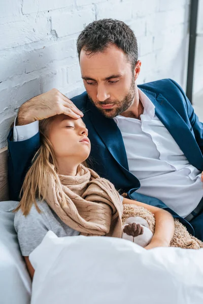 Atento padre tocando la frente de hija enferma - foto de stock