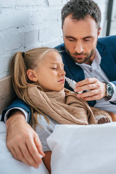 Père attentif tenant pulvérisation nasale près fille malade — Photo de stock