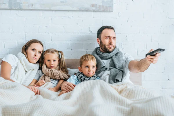 Kranke Familie liegt im Bett und schaut gemeinsam fern — Stockfoto