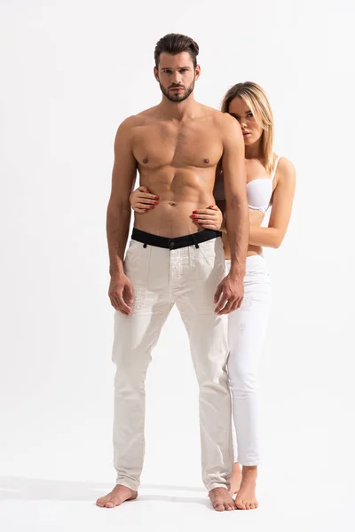 Чувственная женщина обнимает без рубашки тело мужчины на белом — стоковое фото