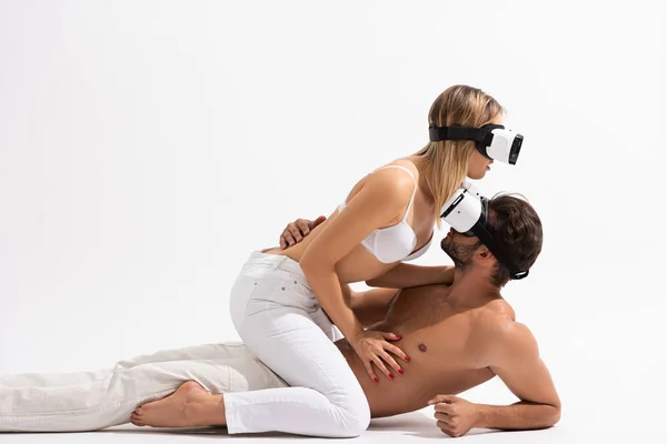 Sexy couple in Virtual reality headsets hugging on white — Stock Photo