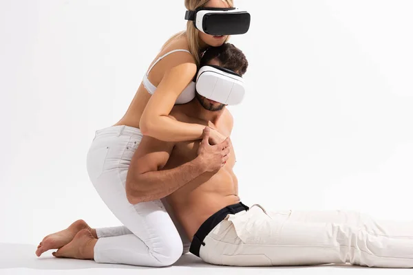 Belo casal sexy em realidade virtual headsets abraçando no branco — Fotografia de Stock