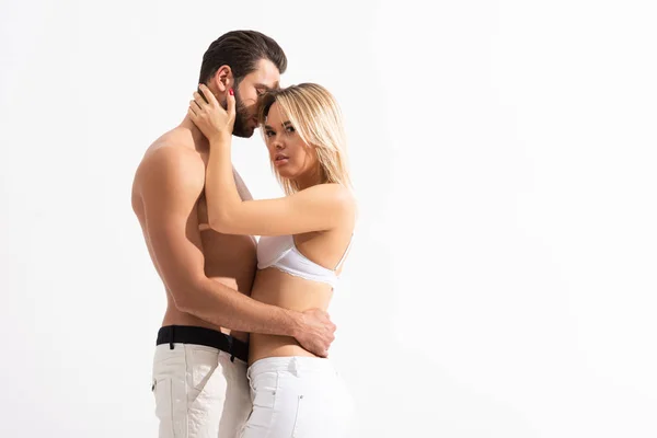 Beautiful seductive couple in white jeans hugging isolated on white — Stock Photo
