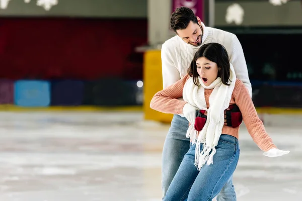 Hombre guapo captura asustado caída mujer en pista de patinaje - foto de stock