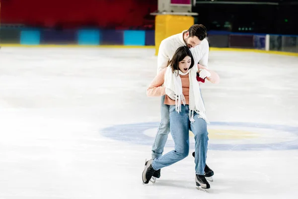 Jovem bonito homem captura queda mulher no skating rinque — Fotografia de Stock
