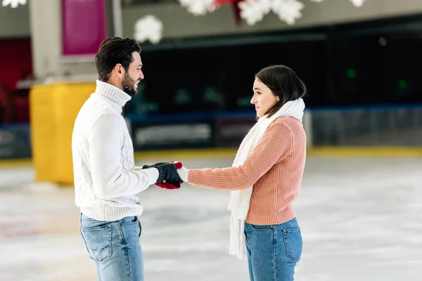 Bella coppia felice che si tiene per mano sulla pista di pattinaggio — Foto stock