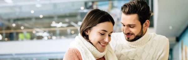 Panoramic shot of young couple in sweaters spending time on skating rink — Stock Photo