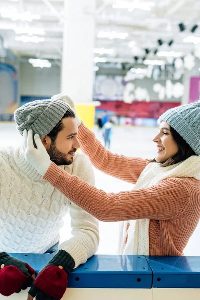 Happy smiling couple wearing hats on skating rink — Stock Photo