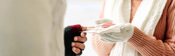 Vue recadrée du couple tenant une carte de vœux le jour de la Saint-Valentin sur la patinoire, prise de vue panoramique — Photo de stock