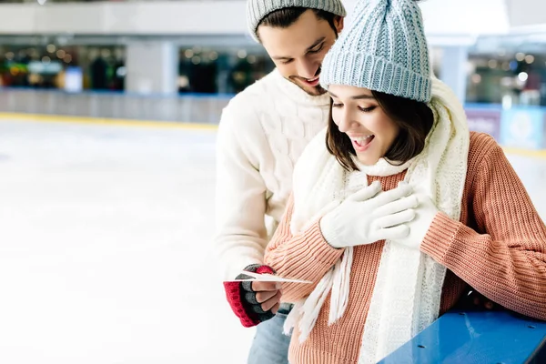 Glücklicher Mann übergibt am Valentinstag Glückwunschkarte an aufgeregte Frau auf Eisbahn — Stockfoto