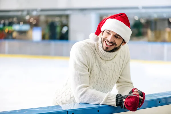 Щасливий чоловік в светрі і капелюсі Санта на ковзанах — стокове фото