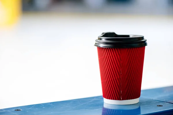 Красная одноразовая чашка кофе, чтобы идти стоя на перилах катка — стоковое фото