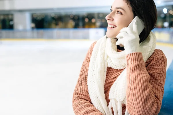 Attraktives lächelndes Mädchen, das auf der Eisbahn mit dem Smartphone spricht — Stockfoto