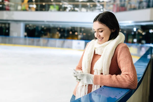 Bela menina feliz usando smartphone na pista de patinação — Fotografia de Stock