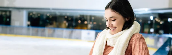 Panoramic shot of beautiful positive girl in scarf standing on skating rink — Stock Photo