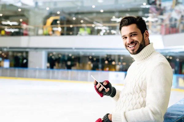 Felice uomo barbuto utilizzando smartphone sulla pista di pattinaggio — Foto stock