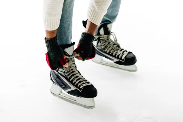 Vue recadrée de l'homme attachant des lacets de patins sur une patinoire — Photo de stock