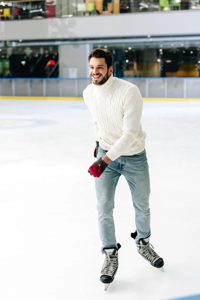 Homme heureux en jeans et pull patinant sur la patinoire — Photo de stock
