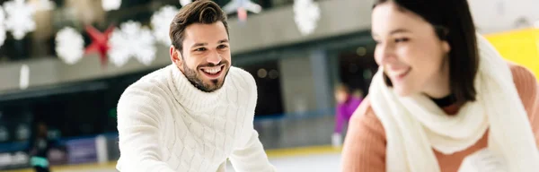 Plano panorámico de feliz pareja divirtiéndose mientras patina en pista de patinaje - foto de stock