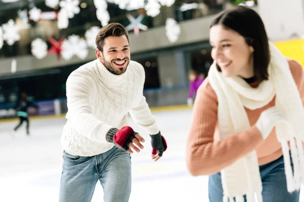 Enfoque selectivo de alegre pareja joven divirtiéndose mientras patina en la pista de patinaje - foto de stock