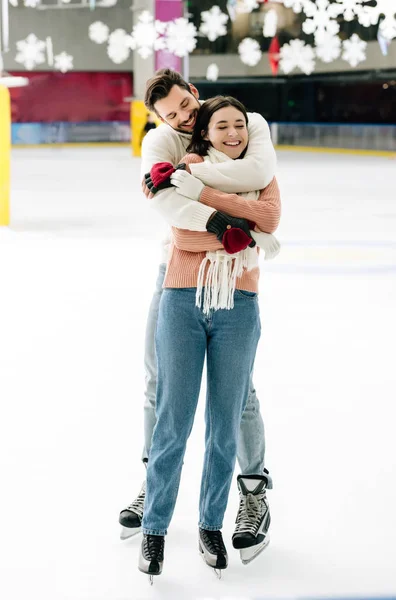 Jovem casal sorridente abraçando e se divertindo na pista de patinação — Fotografia de Stock