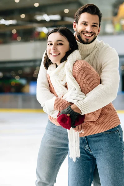 Pareja positiva abrazos y divertirse en pista de patinaje - foto de stock