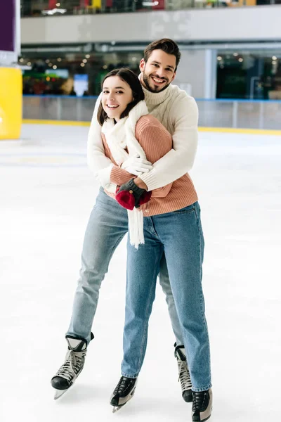 Junges fröhliches Paar umarmt und verbringt Zeit auf der Eisbahn — Stockfoto