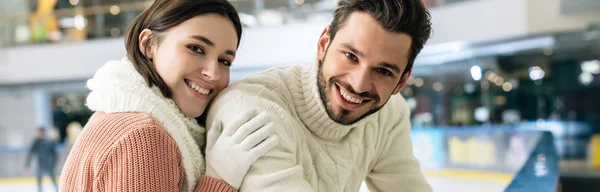 Plano panorámico de alegre pareja en suéteres pasar tiempo en pista de patinaje - foto de stock