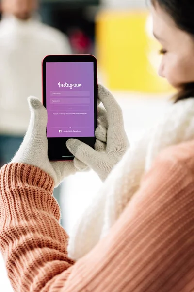 KYIV, UKRAINE - NOVEMBER 15, 2019: cropped view of woman in gloves holding smartphone with instagram app on screen — Stock Photo