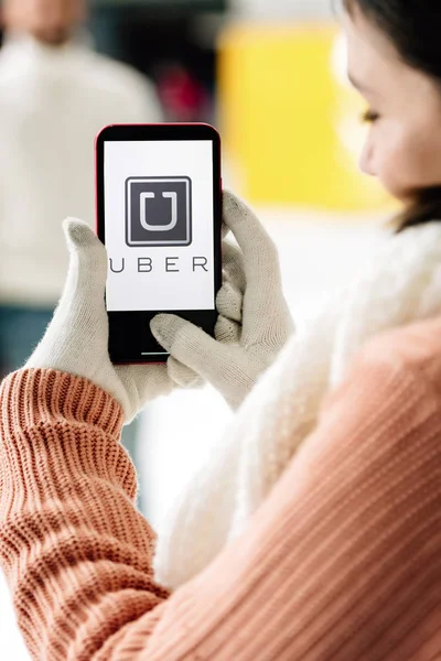 KYIV, UCRAINA - 15 NOVEMBRE 2019: vista ritagliata della donna in guanti che tiene lo smartphone con l'app UBER sullo schermo — Foto stock