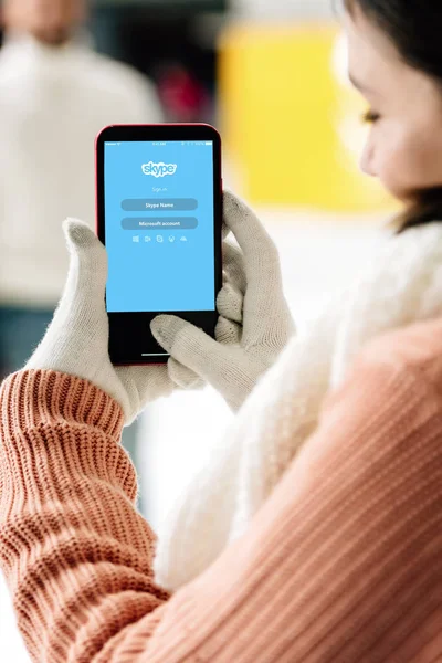 KYIV, UCRAINA - 15 NOVEMBRE 2019: vista ritagliata della donna in guanti che tiene lo smartphone con l'app skype sullo schermo — Foto stock