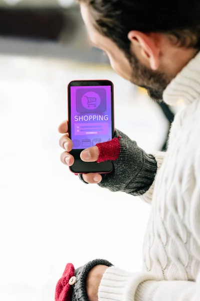 KYIV, UKRAINE - NOVEMBER 15, 2019: cropped view of man in gloves holding smartphone with shopping app on screen, on skating rink — Stock Photo