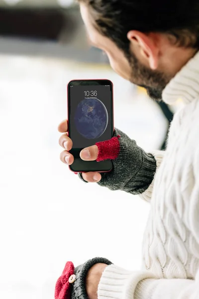 KYIV, UCRANIA - 15 DE NOVIEMBRE DE 2019: vista recortada del hombre con guantes sosteniendo el teléfono inteligente, en la pista de patinaje - foto de stock