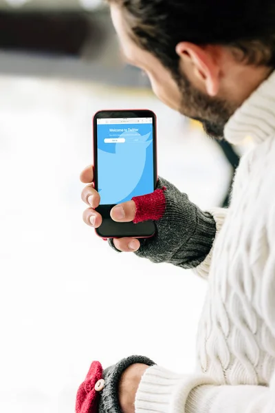 KYIV, UKRAINE - NOVEMBER 15, 2019: cropped view of man in gloves holding smartphone with twitter app on screen, on skating rink — Stock Photo