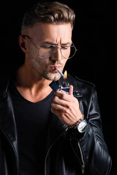 Hombre elegante iluminación cigarrillo con encendedor aislado en negro - foto de stock