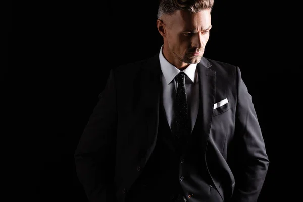 Hombre de negocios guapo serio mirando hacia otro lado aislado en negro - foto de stock