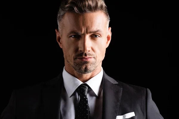 Confident businessman in formal wear looking at camera isolated on black — Stock Photo