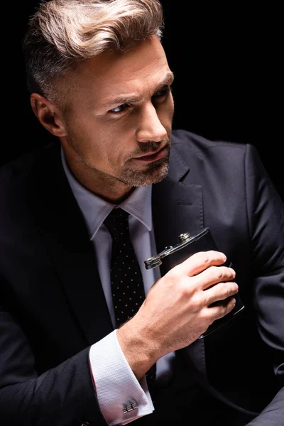 Handsome businessman holding flask isolated on black — Stock Photo