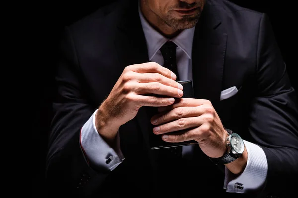 Cropped view of businessman opening flask isolated on black — Stock Photo