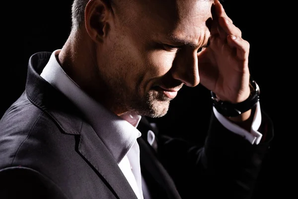 Side view of businessman with hand by head isolated on black — Stock Photo