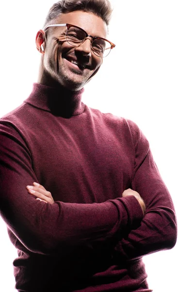 Hombre guapo en auriculares inalámbricos con brazos cruzados sonriendo a la cámara aislada en blanco - foto de stock